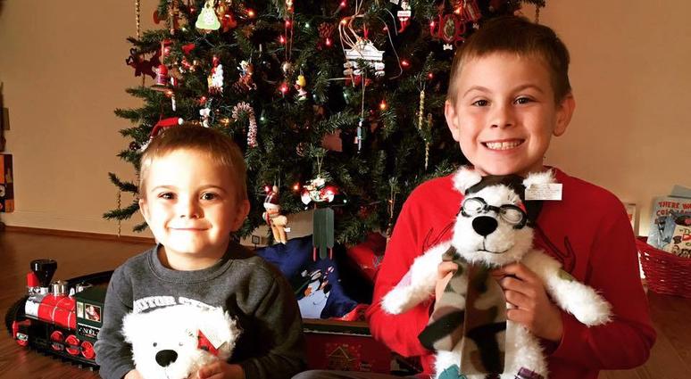 Two boys proudly display their "Cuzzie" bears received in a Comfort Crew 4 Military Kids kit Comfort Crew for Military Kids offers kits featuirng books, stuffed animals, and more to help military children deal with difficult situations