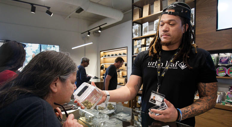 Kerry Durrell, 61, inspects marijuana held by "budtender" Pierce Hunter at Urbn Leaf in San Diego, Calif. dispensary