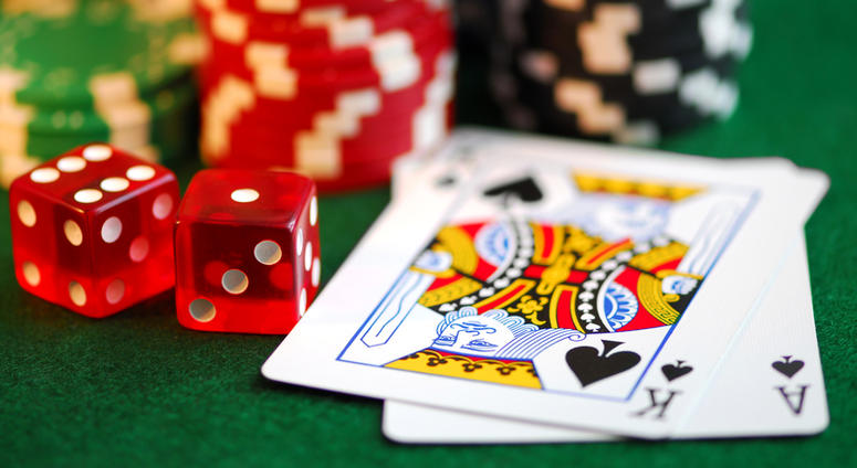 Stacks of gambling chips, playing cards and dice on green background