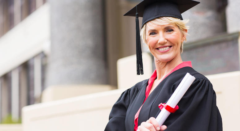 Happy middle aged woman with graduation cap and gown holding diploma