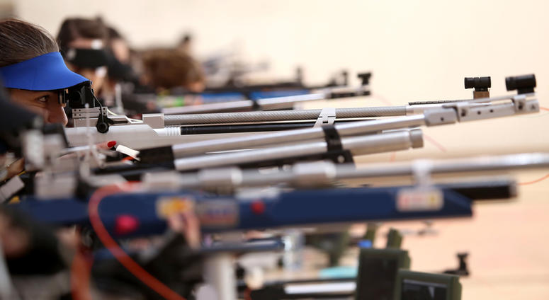 Young woman aiming a pneumatic air rifle on sports competition