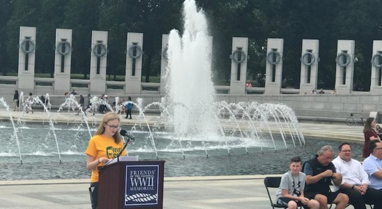 An unidentified woman reads the names of WWII soldiers who died on D-Day.