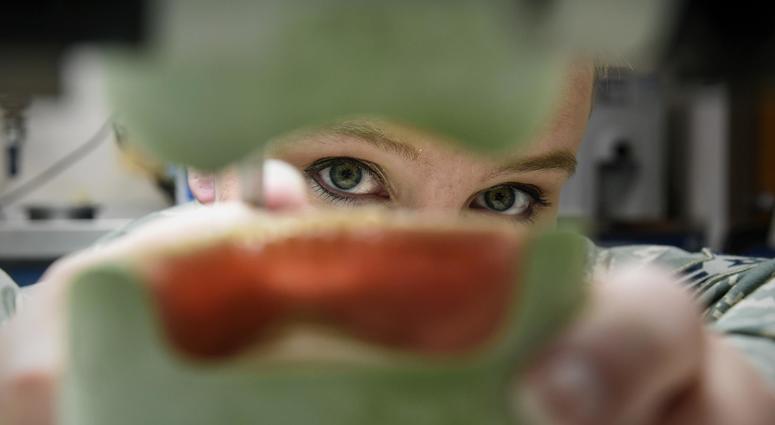 Senior Airman Angelique Culver, a 59th Dental Support Squadron dental lab technician, examines dentures at Joint Base San Antonio-Lackland, Texas,