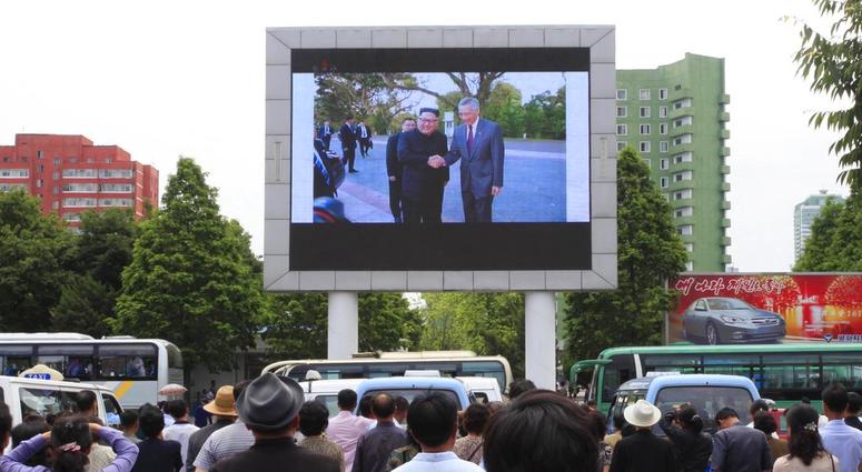 People watch a large screen at the main train station airing video of North Korean leader Kim Jong Un being greeted by Singapore Prime Minister Lee Hsien Loong in Pyongyang, North Korea, DO NOT USE
