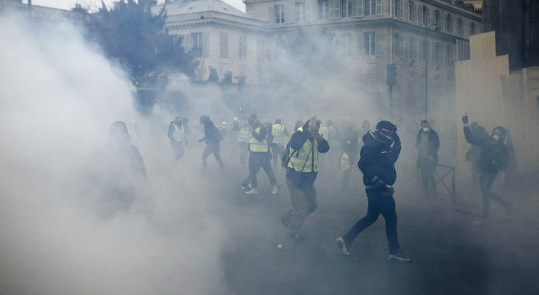 Demonstrators run as tear gas is thrown by riot police during a protest in Paris, Saturday, Jan. 5, 2019. Hundreds of protesters were trying to breathe new life into France's apparently waning yellow vest movement with marches in Paris and gatherings in o Demonstrators run as tear gas is thrown by riot police during a protest in Paris, Saturday, Jan. 5, 2019. Hundreds of protesters were trying to breathe new life into France's apparently waning yellow vest movement with marches in Paris and gatherings in o