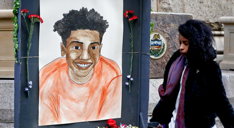 A woman who did not want to be identified holds a memorial display with a drawing of Antwon Rose II in front of the court house on the first day of the trial for Michael Rosfeld, a former police officer in East Pittsburgh, Pa. AP DO NOT USE