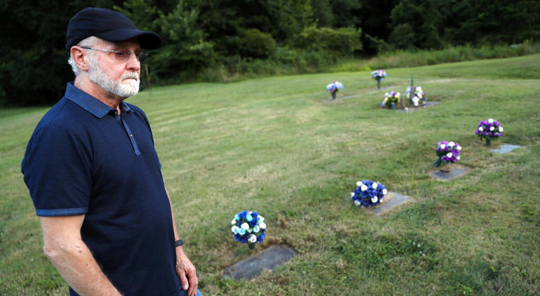 Eddie Davis stands beside the gravestone of his son Jeremy, furthest left, who died from the abuse of opioids, Wednesday, July 17, 2019, in Coalton, Ohio. AP DO NOT USE