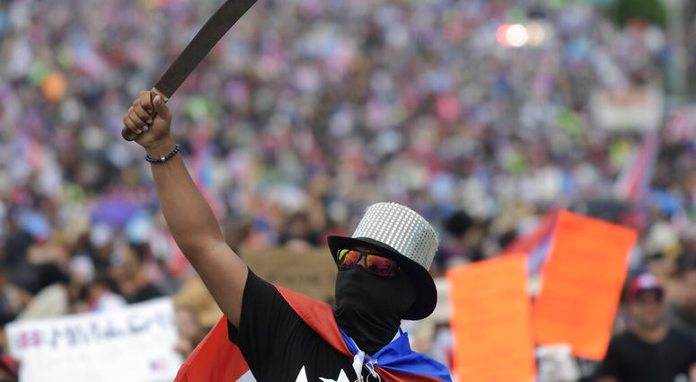 A demonstrator brandishes a machete during a march on Las Americas highway to demand the resignation of governor Ricardo Rossello, in San Juan, Puerto Rico, Monday, July 22, 2019. AP DO NOT USE