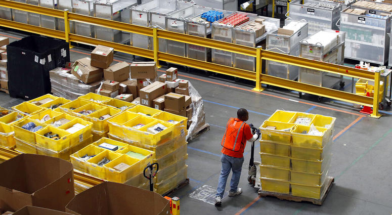 a worker pushes bins at an Amazon fulfillment center in Baltimore. a worker pushes bins at an Amazon fulfillment center in Baltimore.