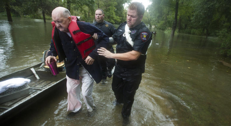 Fred Stewart, left, is helped to high ground by Splendora Police officer Mike Jones after he was rescued from his flooded neighborhood as rains from Tropical Depression Imelda inundated the area, Thursday, Sept. 19, 2019, in Splendora, Texas. AP DO NOT USE