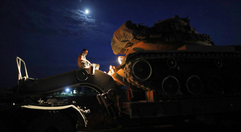 A Turkish army officer prepares to upload a tank from a truck to its new position on the Turkish side of the border between Turkey and Syria, in Sanliurfa province, southeastern Turkey, Tuesday,