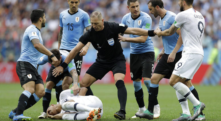 Uruguay players protest to referee Nestor Pitana of Argentina that France's Kylian Mbappe, on the ground, is overreacting after taking a dive during the quarterfinal match between Uruguay and France at the 2018 soccer World Cup DO NOT USE