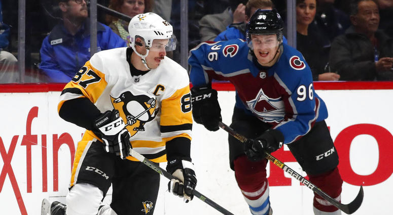 Pittsburgh Penguins center Sidney Crosby, left, picks up a loose puck as Colorado Avalanche right wing Mikko Rantanen defends in the second period of an NHL hockey game Wednesday, Nov. 28, 2018, in Denver. DO NOT USE