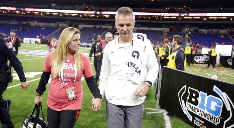 Ohio State head coach Urban Meyer walks off the field with his wife, Shelley Meyer, early Sunday, Dec. 2, 2018, after defeating Northwestern in the Big Ten championship NCAA college football game in Indianapolis. Ohio State won 45-24. DO NOT USE