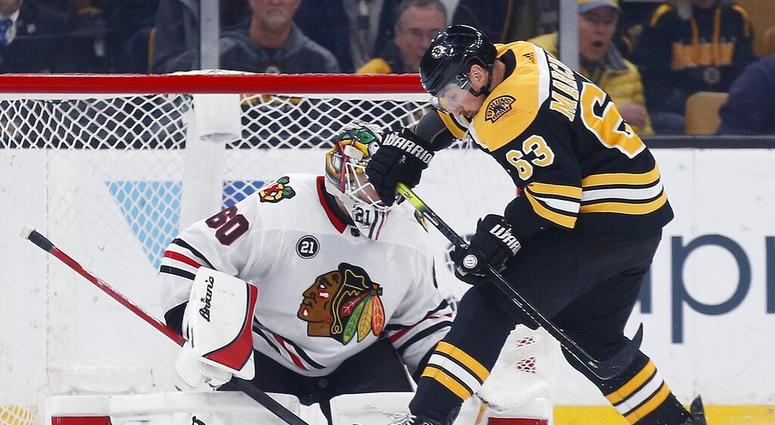 Boston Bruins' Brad Marchand (63) tries to get a shot on Chicago Blackhawks' Collin Delia (60) during the first period of an NHL hockey game in Boston, Tuesday, Feb. 12, 2019. AP DO NOT USE