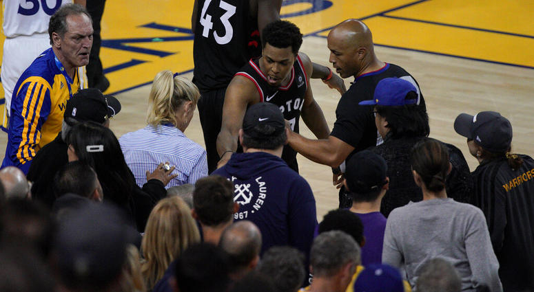 Toronto Raptors guard Kyle Lowry, middle, gestures next to referee Marc Davis (8) near the front row of fans during the second half of Game 3 of basketball's NBA Finals between the Golden State Warriors and the Raptors in Oakland, Calif. AP DO NOT USE