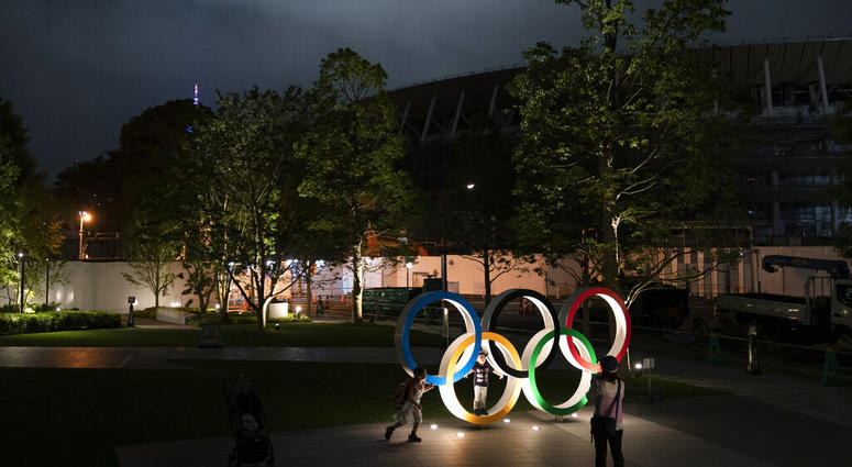 Two children pose for photos with the Olympic Rings in front of New National Stadium in Tokyo, June 23, 2019. AP DO NOT USE