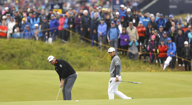 Northern Ireland's Graeme McDowell, left putts on the 14th green watched by Xander Schauffele of the United States during the first round of the British Open Golf Championships at Royal Portrush in Northern Ireland, Thursday, July 18, 2019.