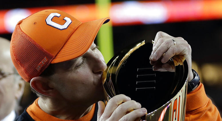 FILE - In this Jan. 7, 2019, file photo, Clemson head coach Dabo Swinney kisses the championship trophy after the NCAA college football playoff championship game against Alabama in Santa Clara, Calif.
