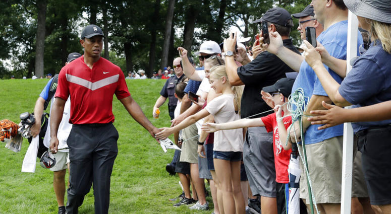 Tiger Woods, left, greets fans as he walks to the 14th fairway after hitting his tee shot during the final round of the BMW Championship golf tournament at Medinah Country Club, Sunday, Aug. 18, 2019, in Medinah, Ill. ap do not use