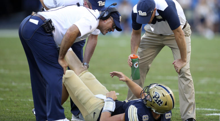 Pittsburgh Panthers quarterback Kenny Pickett (8) is attended to by team trainers and head coach Pat Narduzzi (L) after suffering an apparent leg injury against the Albany Great Danes