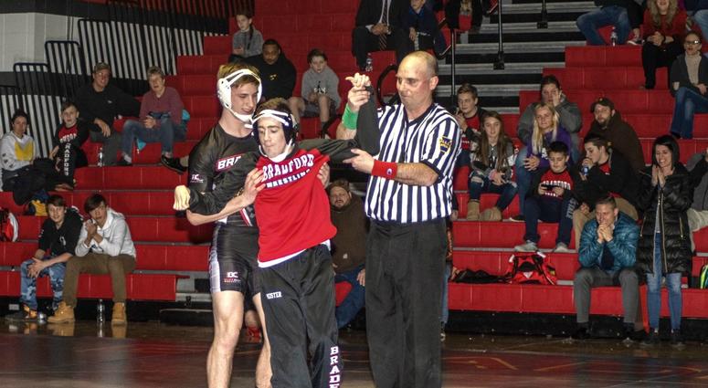 Dillon Keane and a referee raise the hand of Jacob Meister in victory.