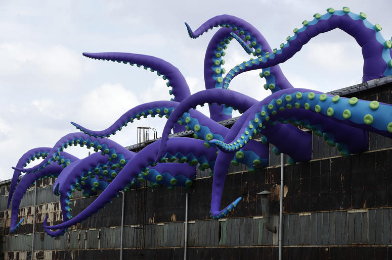 AP18282677483395 An inflatable sculpture entitled "Sea Monsters HERE" extends from a rusting warehouse called Building 61 at the Navy Yard in Philadelphia, Tuesday, Oct. 9, 2018. The installation was created by UK-based artists Filthy Luker and Pedro Estrellas. The former
