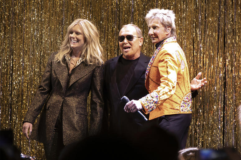 AP19044651509947 Designer Michael Kors, center, is joined by model Patti Hansen and Barry Manilow on stage after his collection was modeled during Fashion Week in New York, Wednesday, Feb. 13, 2019. (AP Photo/Richard Drew)