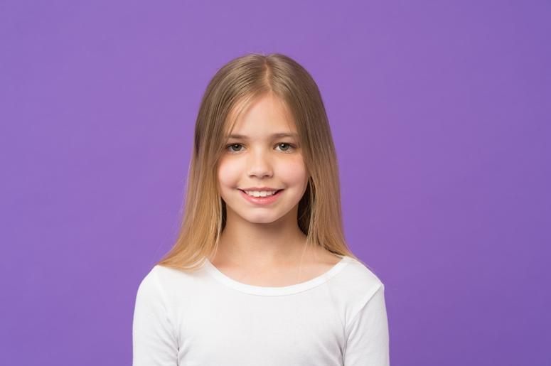 Girl with beautiful smile isolated on purple background. Child with cute face studio portrait. Model with shining blonde Girl with beautiful smile isolated on purple background. Child with cute face studio portrait. Model with shining blonde