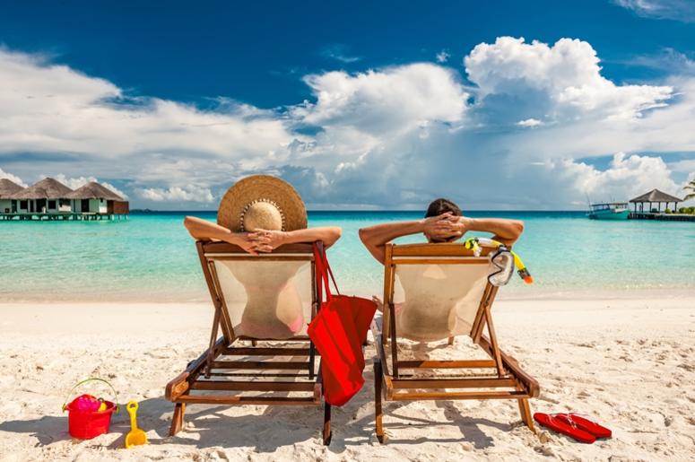 Couple in loungers on beach at Maldives Couple in loungers on beach at Maldives
