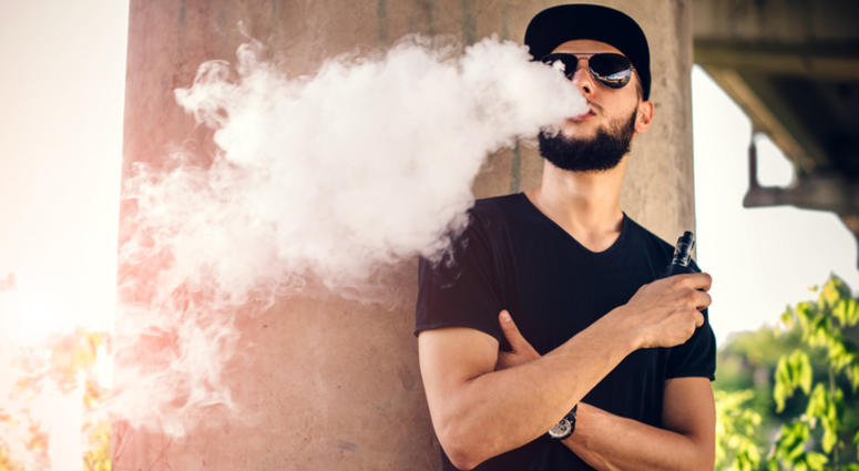 Young man blows huge cloud of steam from vaping device