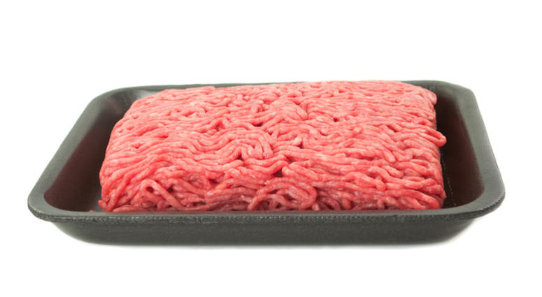 A tray of fresh lean ground beef from supermarket on white background