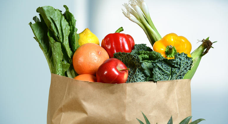grocery Assortment of fresh produce in grocery paper bag by window