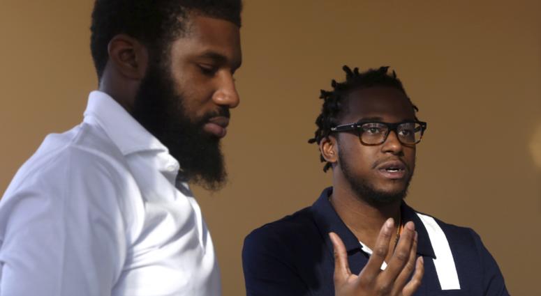 In this Wednesday, April 18, 2018 photo, Rashon Nelson, left, listens as and Donte Robinson, right, addresses a reporter's question during an interview with The Associated Press in Philadelphia. Their arrests at a local Starbucks quickly became a viral vi