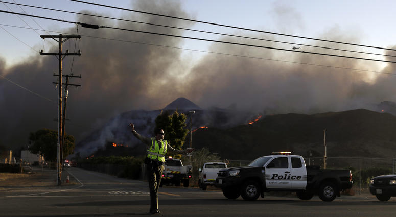 A police officer mans a checkpoint in front of an advancing wildfire Thursday, Nov. 8, 2018, near Newbury Park, Calif. A police officer mans a checkpoint in front of an advancing wildfire Thursday, Nov. 8, 2018, near Newbury Park, Calif.