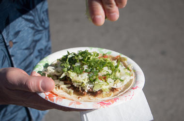 Señora Come Tacos Con Tijeras A lime is being squeezed onto a carne asada taco on a paper plate.