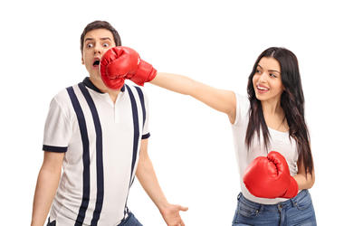 Novia Noquea A su Novio Jugando Al Box Cheerful woman punching her boyfriend with boxing gloves isolated on white background