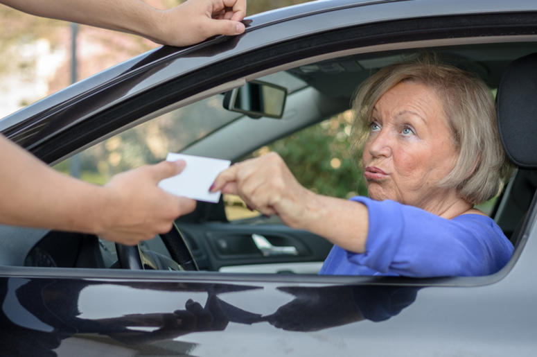 Policía Electrochoca A Abuelita Por Resistirse A Multa Concerned elderly woman driver handing over her licence to a man reaching towards the open window during a road block or after committing a minor offence
