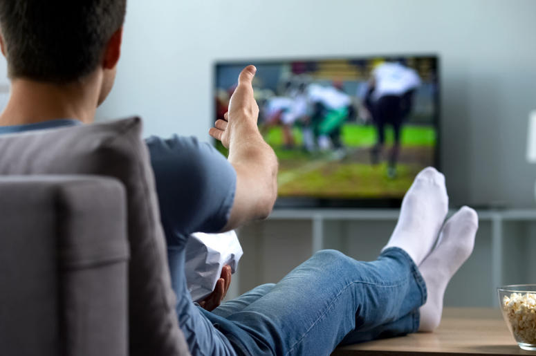 Fan watching football on his couch. Fan watching football on his couch.
