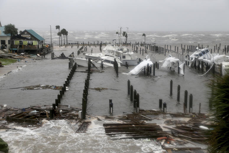 Storm Surge retreats from inland areas, foreground, where boats lay sunk and damaged at the Port St. Joe Marina