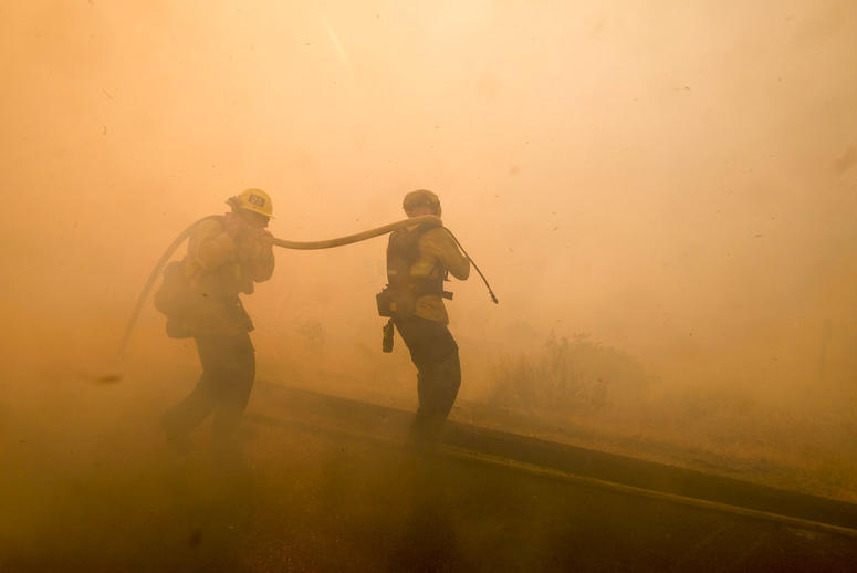 Firefighters battle a fire along the Ronald Reagan (118) Freeway in Simi Valley, Calif.