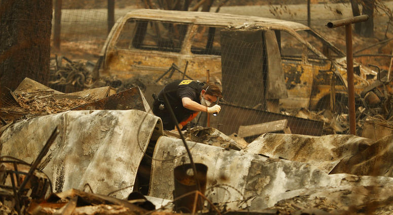A member of the Sacramento County Coroner's office looks for human remains in the rubble of a house burned at the Camp Fire