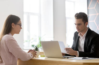 Serious hr attentively reading resume of candidate at job interv