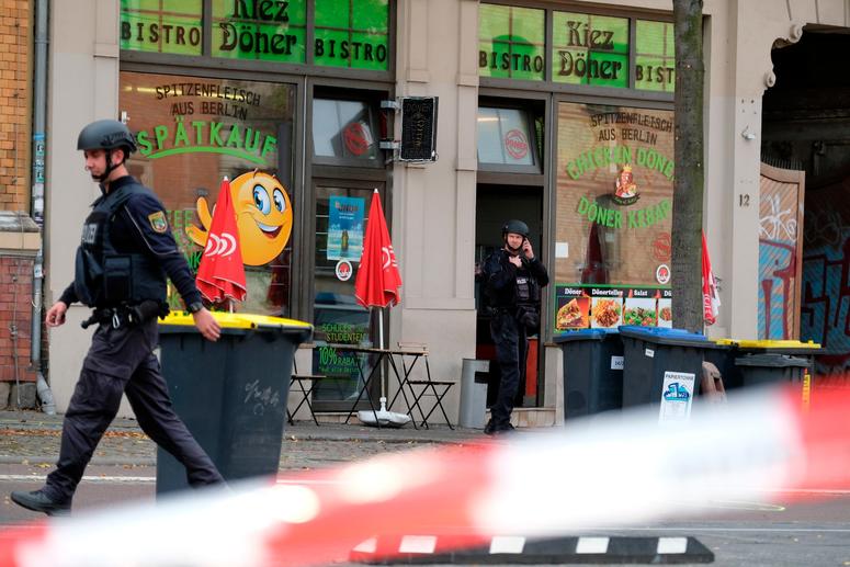 A police officer walks in front of a kebab grill in Halle, Germany, Wednesday, Oct. 9, 2019. A gunman fired several shots on Wednesday in the German city of Halle. Police say a person has been arrested after a shooting that left two people dead. A police officer walks in front of a kebab grill in Halle, Germany.