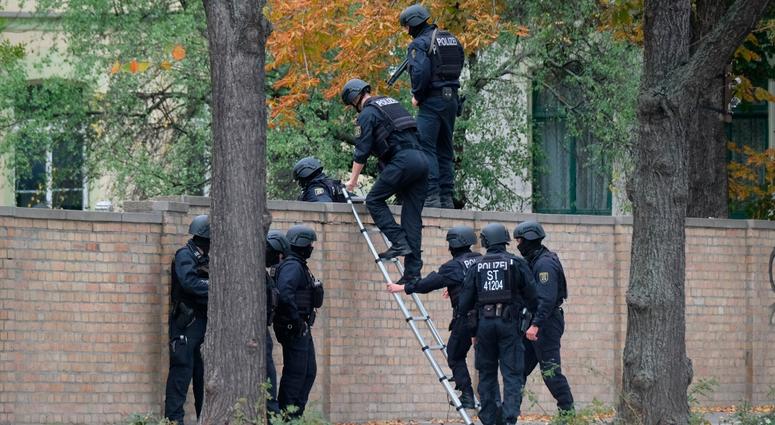 Police officers cross a wall at a crime scene in Halle, Germany, Wednesday, Oct. 9, 2019 after a shooting incident. Police officers in Halle, Germany