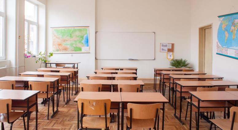 Empty classroom interior with wooden desks and chairs, maps and white board Empty classroom interior with wooden desks and chairs, maps and white board