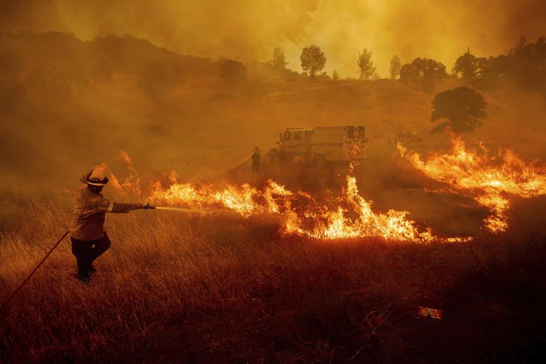 A firefighter scrambles to stop a wildfire as wind drives embers across Highway 20 near Clearlake Oaks, Calif., on Sunday, July 1, 2018. A firefighter scrambles to stop a wildfire as wind drives embers across Highway 20 near Clearlake Oaks, Calif., on Sunday, July 1, 2018.