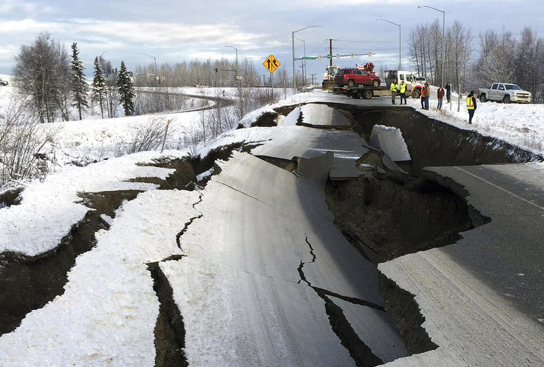A tow truck holds a car that was pulled from on an off-ramp that collapsed during a morning earthquake on Friday, Nov. 30, 2018, in Anchorage, Alaska. Alaska Earthquake
