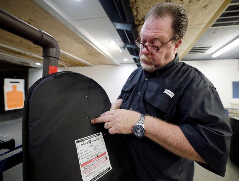 Steve Naremore, founder and CEO of TuffyPacks, shows the impact points on a ballistic shield retrieved from a backpack after a shooting demonstration of the stopping ability of the product at the Shiloh Shooting Range, Friday, August 9, 2019, in Houston. Bullet-resistant backpacks