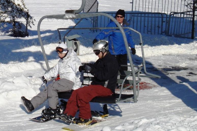 A ski lift attendant helps skiers on and off. A ski lift attendant helps skiers on and off.
